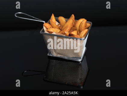 Patate fritte cunei su metacrilato nero nel cestello di metallo vista superiore Foto Stock