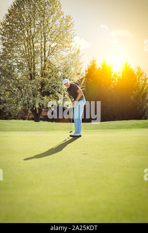 Vecchio giocatore di golf putting sul verde. Foto Stock