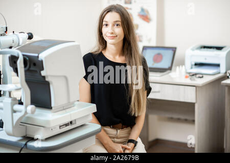 Ritratto di un allegro giovane donna come un paziente presso l ufficio oftalmologica, attesa per occhio diagnostica con oculista Foto Stock
