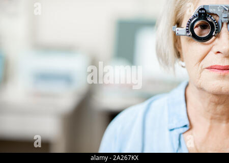 Close-up di un senior donna controllando la visione con occhio occhiali di prova nel corso di un esame medico presso l ufficio oftalmologica Foto Stock