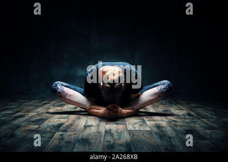 Giovane donna a praticare yoga facendo reclinato dea pongono asana in camera oscura. Supta Baddha Konasana. Benessere e uno stile di vita sano Foto Stock