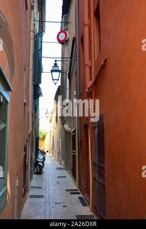 Piccolo vicolo stretto con orange case e uno scooter nella città vecchia di Saint Tropez, Francia Foto Stock