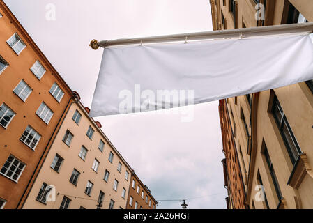 Bianca orizzontale banner vuoto sul negozio di abbigliamento fronte contro di vecchi edifici in città Foto Stock