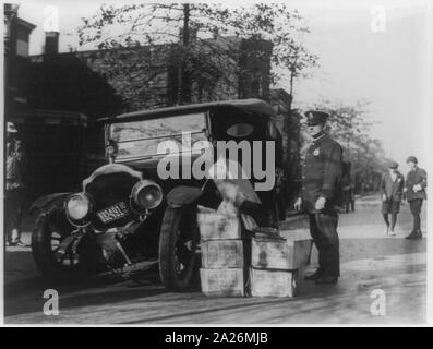 Poliziotto in piedi accanto ad auto disastrate e casi di moonshine Foto Stock