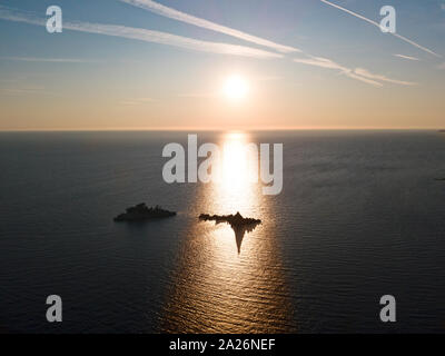 Vista aerea al tramonto delle due piccole isole al largo della costa del Montenegro, vicino a Petrovac. Parco vicino a Katic e alla chiesa di Santa Nedjelja Foto Stock