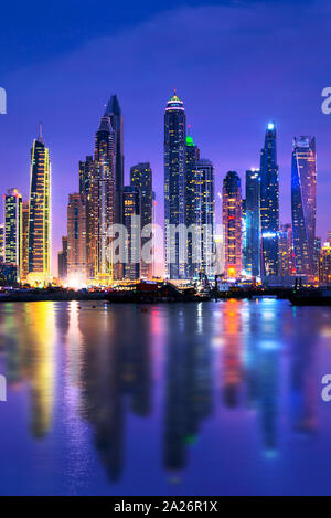 Marina di Dubai skyline notturno con acqua riflessioni, Emirati Arabi Uniti Foto Stock