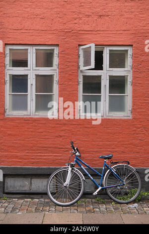 Bicicletta appoggiata contro la casa nella città di Copenaghen su un nuvoloso giorno di autunno, Danimarca Foto Stock