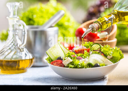 Olio di oliva di versare alla verdura fresca insalata. Mediterraneo sano italiano o cucina greca Foto Stock