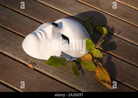 Ancora vita autunno umore foto con vintage white paper maschera e foglie su sfondo di legno Foto Stock