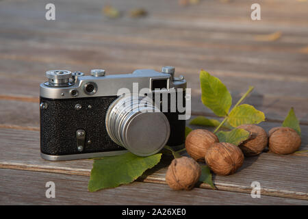 Ancora vita autunno umore foto con telemetro vintage fotocamera, le foglie e i dadi su sfondo di legno Foto Stock