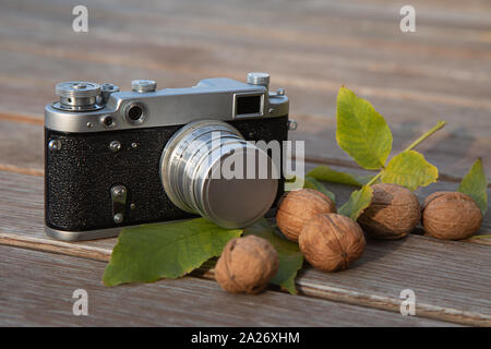 Ancora vita autunno umore foto con telemetro vintage fotocamera, le foglie e i dadi su sfondo di legno Foto Stock