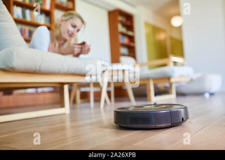 Vuoto robot aspirapolvere il pavimento in parquet nel soggiorno Foto Stock