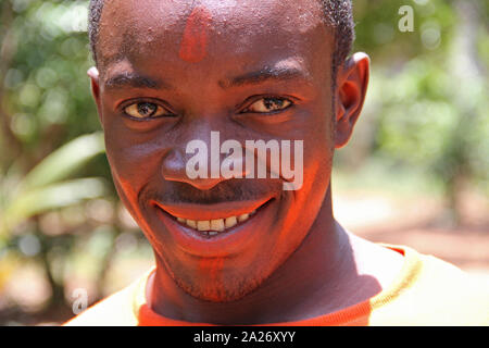 Farm locale lavoratore con achiote rosso colorante sulla sua fronte, Spice Farm, Zanzibar, Tanzania. Foto Stock
