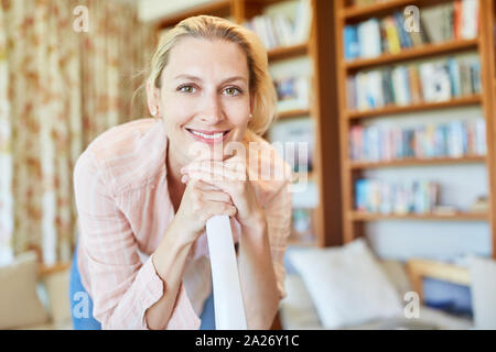 Sorridente massaia o detergente con aspirapolvere nella stanza vivente Foto Stock