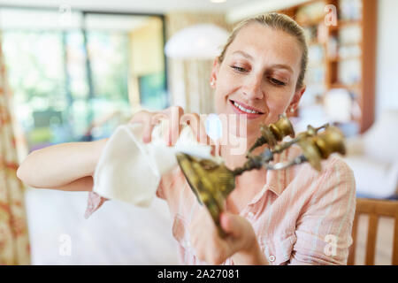 Cameriera o casalinga pulisce e lucida un ottone portacandele Foto Stock