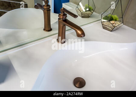 Il sapone e lo shampoo dispenser vicino ceramica rubinetto acqua lavandino con rubinetto in costosi loft bagno Foto Stock