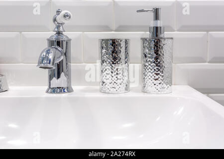 Il sapone e lo shampoo dispenser vicino ceramica rubinetto acqua lavandino con rubinetto in costosi loft bagno Foto Stock