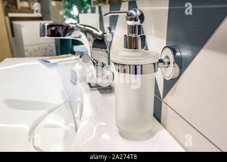 Il sapone e lo shampoo dispenser vicino ceramica rubinetto acqua lavandino con rubinetto in costosi loft bagno Foto Stock