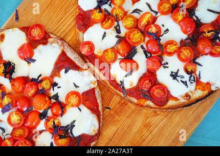 Pizza con freschi pomodori ciliegia, mozzarella e basilico opale su una crosta di cavolfiore Foto Stock