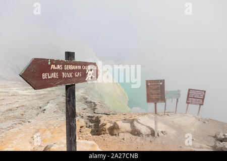 Cartello di avvertimento a wastelands in Kawah Ijen cratere del vulcano a miniera di zolfo. Post apocalisse il paesaggio con le nubi di gas tossici dal vulcano Foto Stock