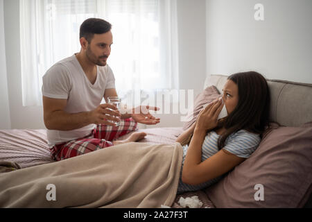 La donna è malato, l uomo è la sua gaving pillole. Foto Stock