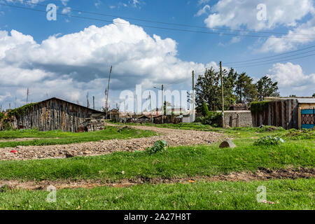 Nanyuki, Contea di Laikipia, Kenya - Giugno 19th, 2019: fotografia paesaggio di pietra via circondato da tipici di piccole case keniota in Nanyuki periferia. Foto Stock
