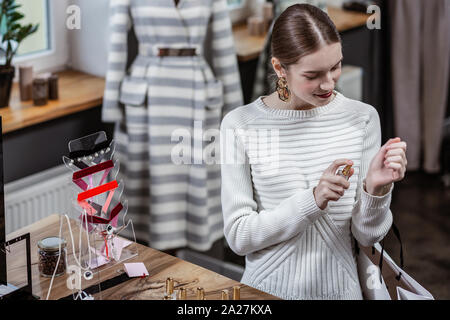 Allegro giovane donna spruzzare profumo sul suo polso in negozio Foto Stock