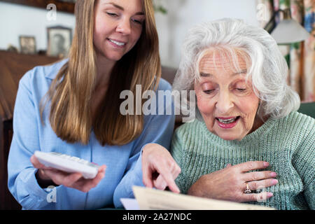 Donna aiutando Senior il prossimo con fatture e documenti Foto Stock