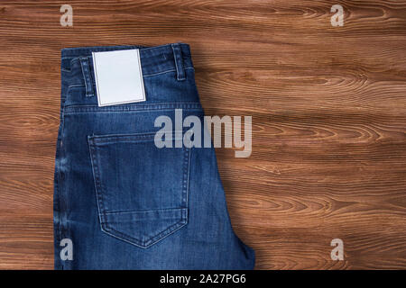 Etichetta di jeans mockup, denim texture, isolato sullo sfondo di legno Foto Stock