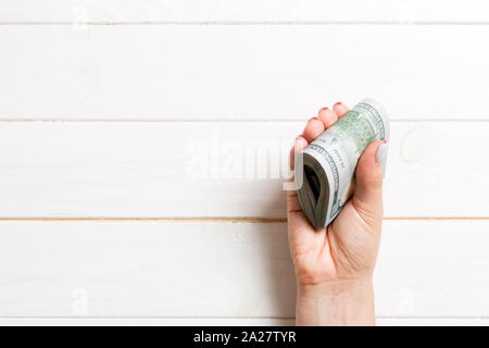 Un pacco di banconote da cento dollari in mano femmina su sfondo di legno. Concetto di stipendio con copia spazio. Foto Stock