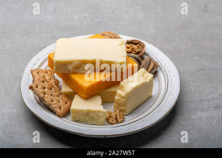 Raccolta di formaggio, maturato e arancione originale British il formaggio cheddar in blocchi servito con cracker close up Foto Stock