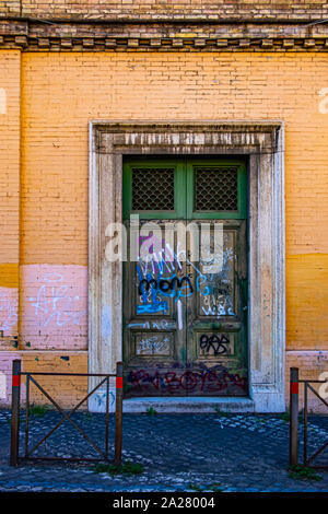 Fortemente graffitied porta verde con scrittura multicolore, all'interno di un edificio color crema dipinse anche in luoghi. Arte di strada o atti di vandalismo. Foto Stock