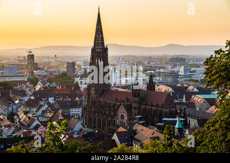 Germania, foresta nera città Freiburg im Breisgau a Baden nel fantastico tramonto crepuscolo atmosfera, vista aerea su muenster chiesa da sopra le case Foto Stock