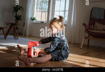 Giovane ragazza che gioca con la finta set caffè a casa nella luce della finestra Foto Stock