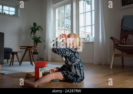 Ragazza giovane a giocare a casa con un giocattolo macchina da caffè Foto Stock