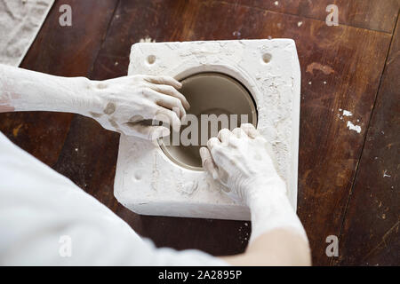 Mani femminili tenere una ciotola per il colaggio di prodotti di argilla. Foto Stock