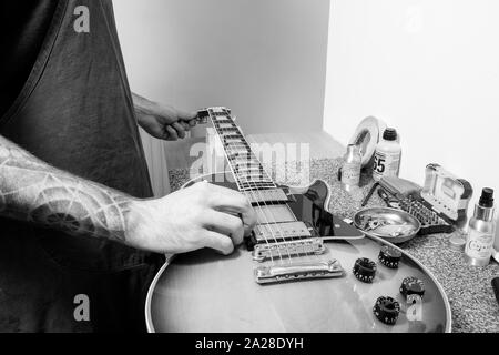 Un tecnico di chitarra o tech tuning una infilate nuovamente Gibson chitarra elettrica nella sua bottega. Lui è la sintonizzazione del tuning post mentre spiumatura la stringa Foto Stock