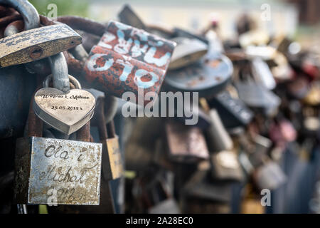 Un mazzetto di rusty amore lucchetti attaccato al ponte. Foto Stock