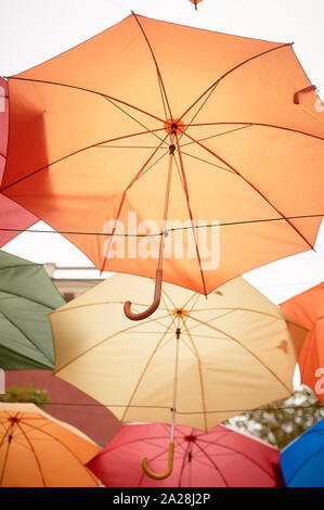 Texture. Un sacco di ombrelloni appesi al cielo. Protezione dal sole e dalla pioggia. Rosso, arancione e blu. Foto Stock