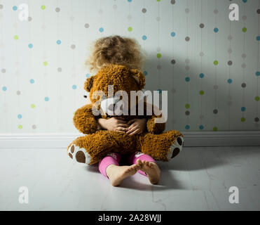 Poco dai capelli ricci ragazza piange in camera sua. Bambina ha bisogno di attenzione. Foto Stock