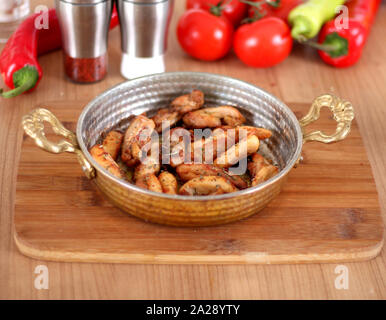 Una foto diversa di pollo fritto che serve in rame e piastra bianca da uno stretto angolo su una tavola di legno Foto Stock