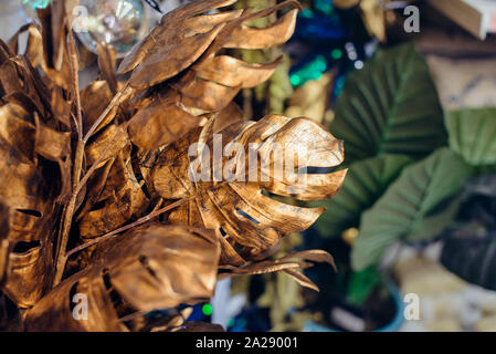 Close up artificiali Monstera tropicale lascia decorazioni sui colorfull sfondo. Moderno e creativo i dettagli interni. Messa a fuoco selettiva. Spazio di copia Foto Stock
