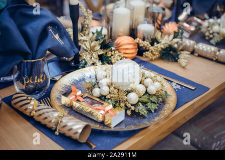 Christmastime impostazione tabella festosa stoviglie decorate con dettagli e palle bianche in blu e i colori dorati. Navy Blue Biancheria da tavola e oro Cutler Foto Stock