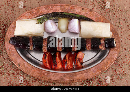 Servire la carne e spiedini di melanzane e cipolle in una ad alto angolo piatto di rame Foto Stock