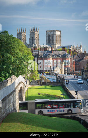 Un parco e di autobus che passa sotto la barra mura di York e oltre, Lendal ponte sopra il fiume Wharfe e York Minster Foto Stock