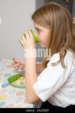 11 anno vecchia ragazza acqua potabile al tavolo da pranzo Foto Stock