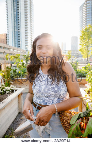 Ritratto fiducioso giovane donna nella soleggiata, urban comunità giardino