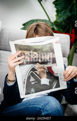 Parigi, Francia - 27 Settembre 2019: Donna di liberazione di lettura nel vivere quotidiano in camera dopo la morte dell ex Presidente francese Jacques Chirac all'età di 86 anni con la mano sul coperchio Foto Stock