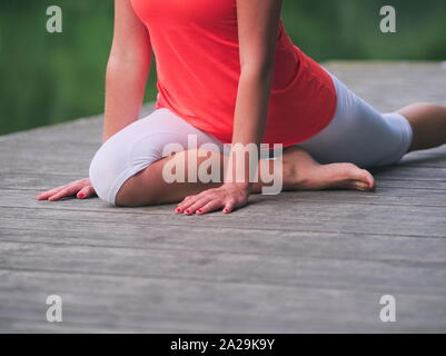 Donna nella sua Anni Trenta facendo Yoga nel Parco su un molo Foto Stock