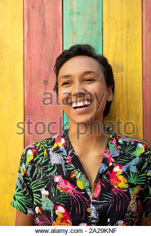 Ritratto felice e spensierato giovane donna in tropical stampa camicetta sul patio estivo